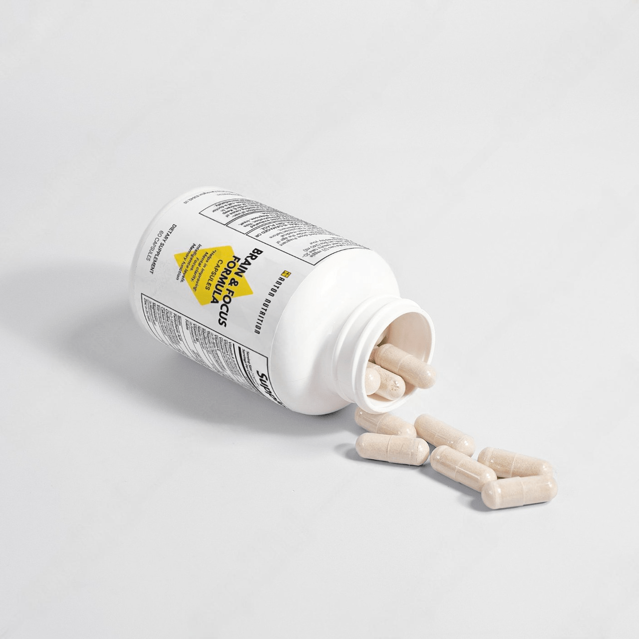 A bottle of Brain & Focus Formula capsules by Anton Nutrition, helping to improve mental clarity, focus, intelligence levels, and memory function, with some capsules spilled out.